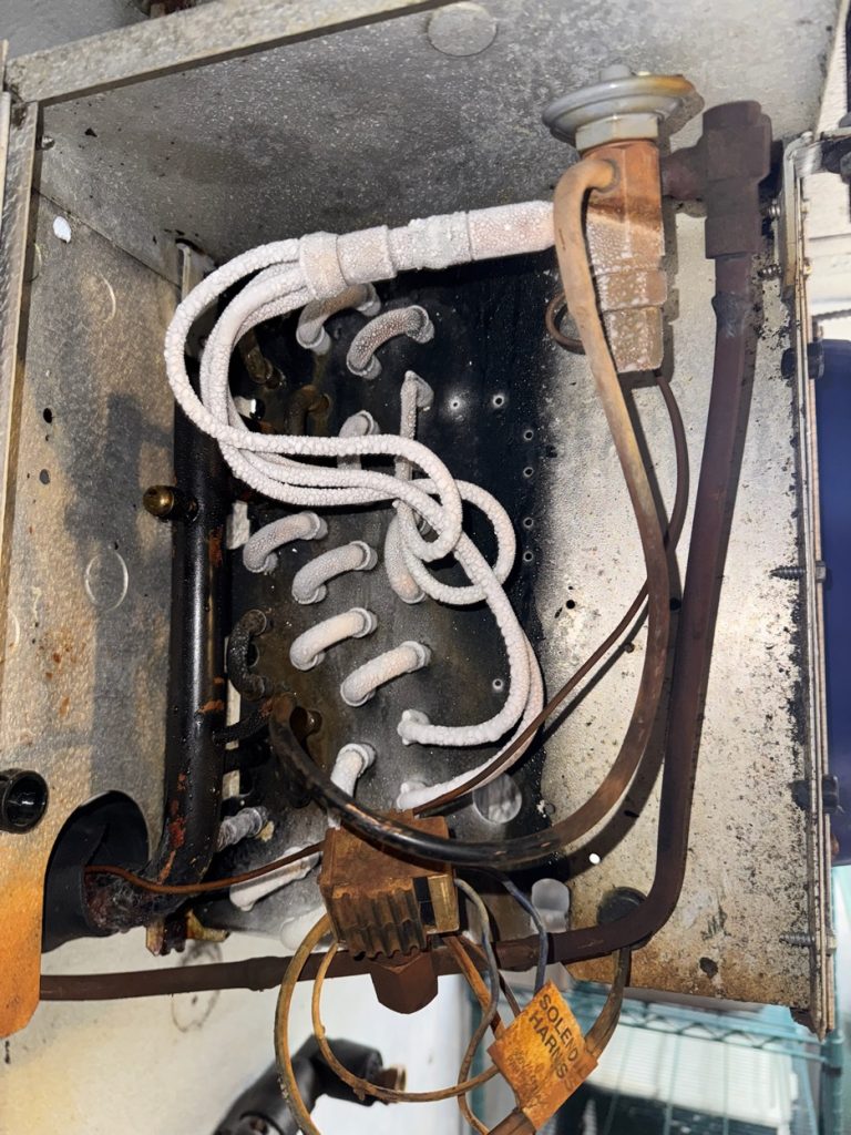 Líneas de refrigerante escarchadas y válvula de expansión dentro de un refrigerador